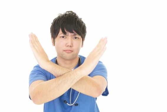 男性の歯科衛生士が×をしている写真